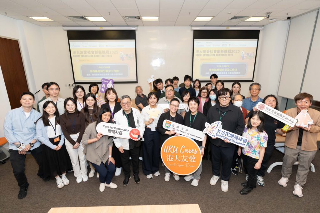 Group photo of participants and organizers at the HKU Social Innovation Challenge 2025, holding banners and signs promoting community care, social enterprise, and innovative collaborations, with event details displayed on presentation screens in the background.