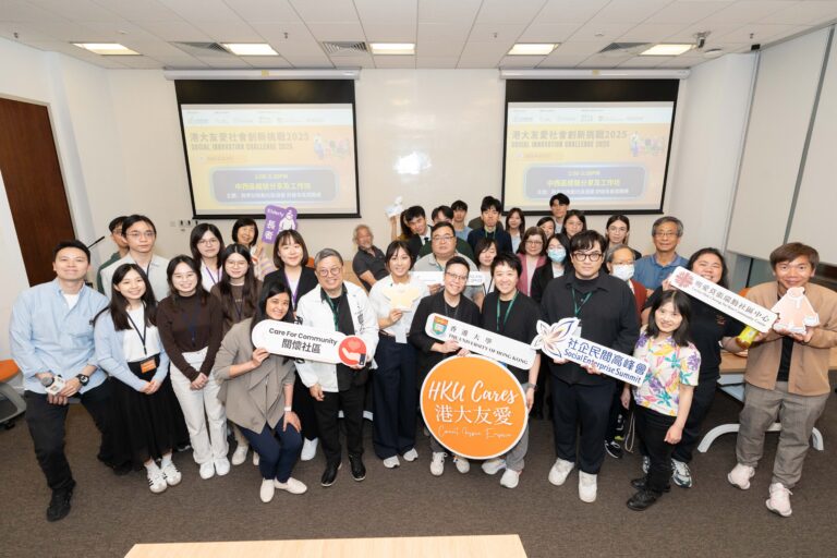 Group photo of participants and organizers at the HKU Social Innovation Challenge 2025, holding banners and signs promoting community care, social enterprise, and innovative collaborations, with event details displayed on presentation screens in the background.